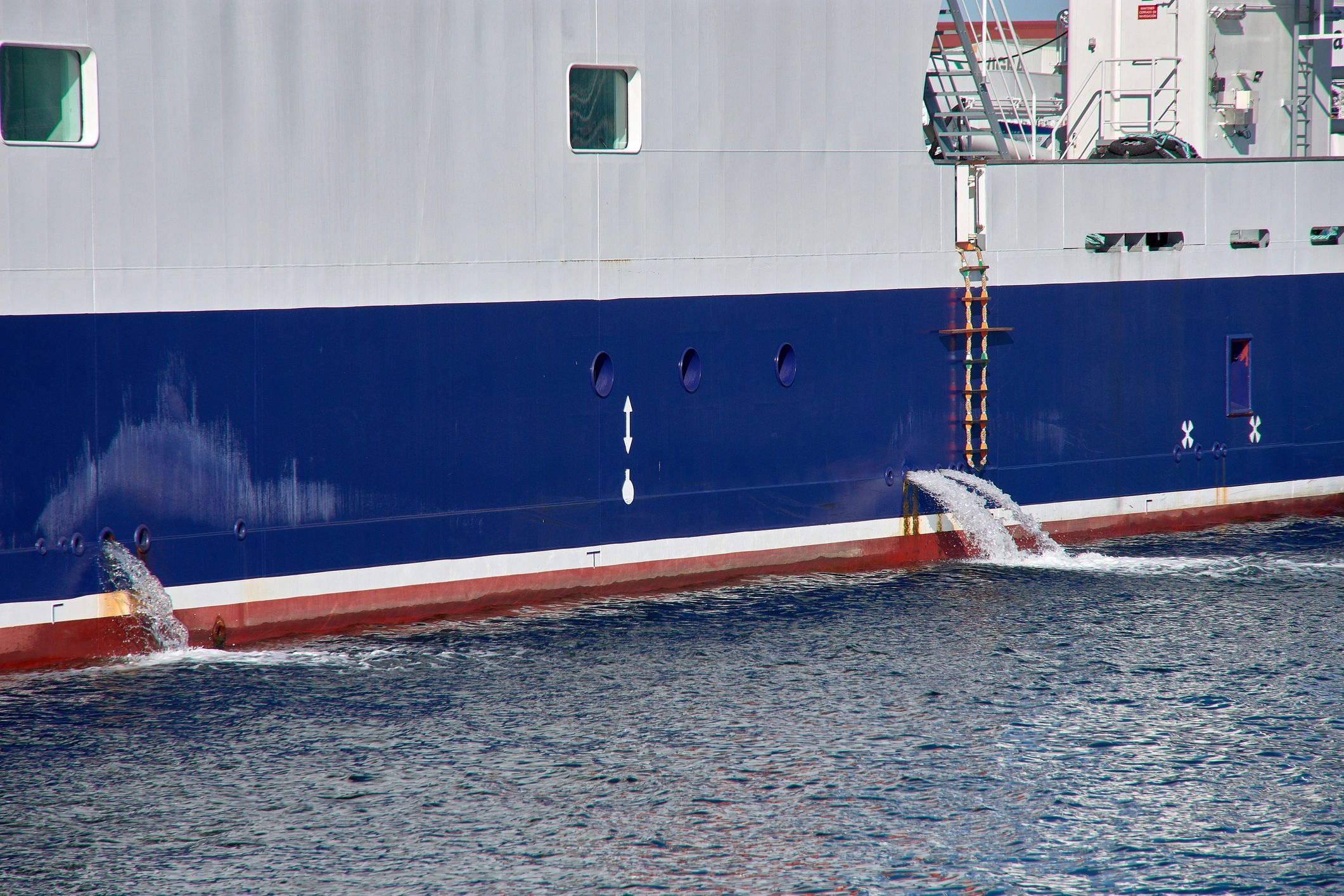 Ship hull discharging ballast water at port