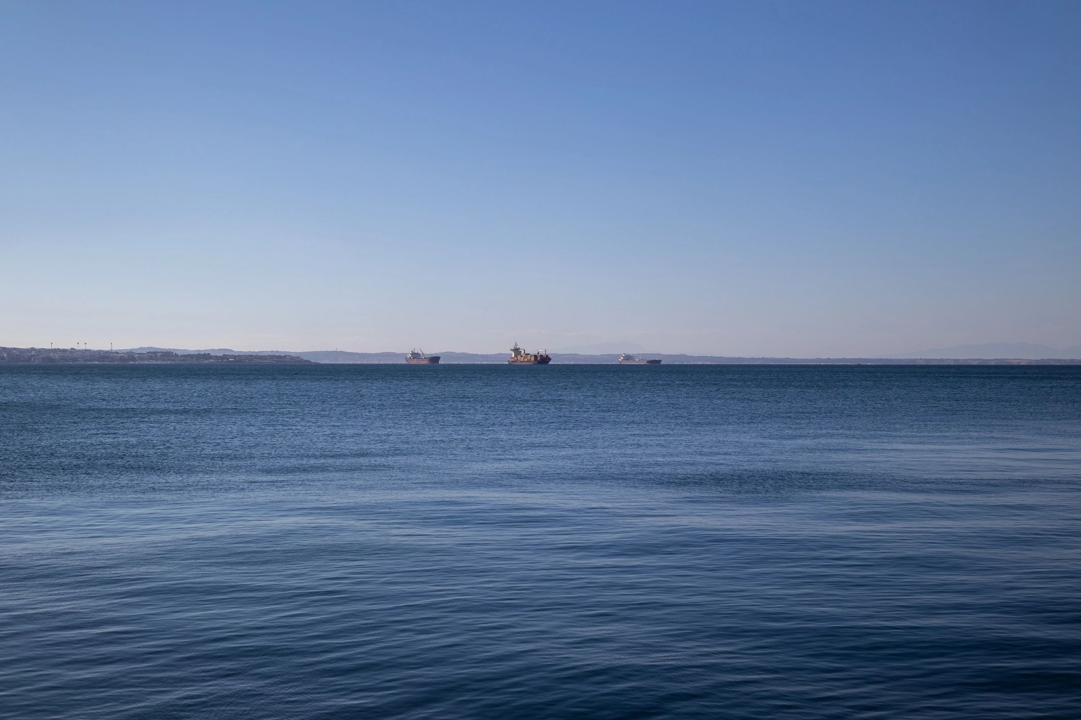 Cargo vessels on the horizon at sea under clear skies