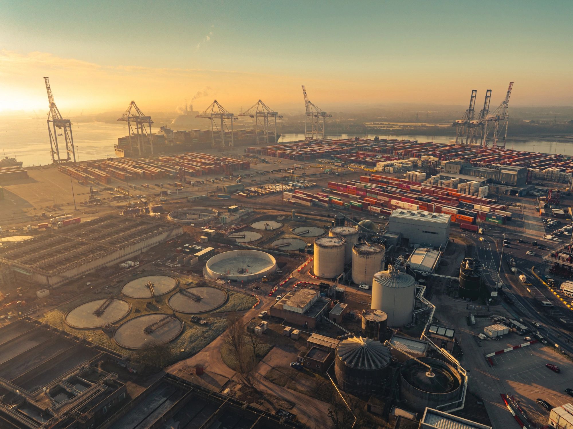 Port container terminal with industrial tanks at dusk